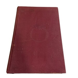 Op de afbeelding: Een bordeauxrood hardback boek met een decoratief ontwerp op de voorkant.