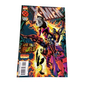 May include: X-Men comic book featuring the title "The Fall of Avalon." The cover art showcases several characters in action, with vibrant colors and dynamic poses. The comic is a direct edition, with the Marvel Comics logo and the July issue date visible.