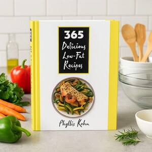 May include: A cookbook titled "365 Delicious Low-Fat Recipes" with a yellow spine and a white cover. The cover features a black rectangle with white text and an image of a plate of food. The author's name, Phyllis Kohn, is below the image.