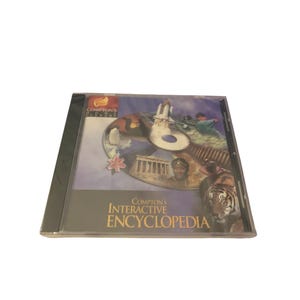 May include: A Compton's Interactive Encyclopedia CD-ROM in a clear plastic jewel case. The cover art features a collage of a space shuttle, a classical building, a tiger, and a person, with the text Compton's Home Library and Interactive Encyclopedia.
