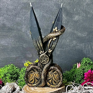 May include: Black and gold candle holder shaped like a pair of scissors with a snake wrapped around the handles. The handles have a pentagram design.