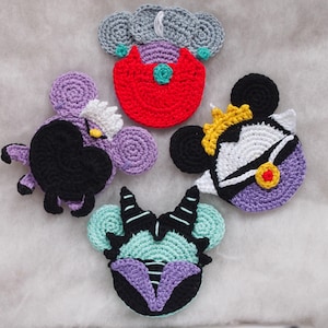 May include: Five crocheted Disney villain character ornaments. The characters are Ursula, Maleficent, Cruella de Vil, Evil Queen, and the Queen of Hearts. Each ornament is purple, black, and white with a different colored accent.