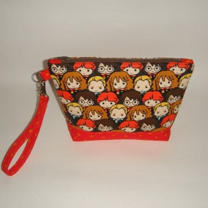 May include: A brown and orange zippered pouch with a red strap. The pouch is covered in a pattern of cartoon characters from the Harry Potter series.
