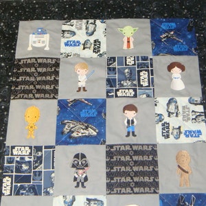 Puede incluir: Una colcha de retazos gris y azul con personajes de Star Wars y el texto "Star Wars" repetido en todo. Los personajes incluyen R2-D2, Yoda, Luke Skywalker, la princesa Leia, Han Solo, Chewbacca, Darth Vader y C-3PO.