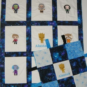 May include: A blue and white baby quilt with a galaxy print. The quilt has nine squares with embroidered images of characters from the Guardians of the Galaxy movie. The quilt also has a small, blue and white tag with the name "Alastair" embroidered on it.