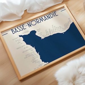 Puede incluir: Un mapa enmarcado de Baja Normandía, Francia, en un estilo minimalista. El mapa es una silueta azul oscuro sobre un fondo crema, con nombres de lugares en una fuente azul oscuro. El marco es de madera clara.