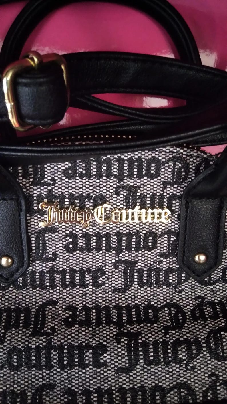 May include: Black and white patterned handbag with black handles and gold hardware. The bag features the text "Juicy Couture" in gold lettering. The bag has a black strap and a gold buckle.
