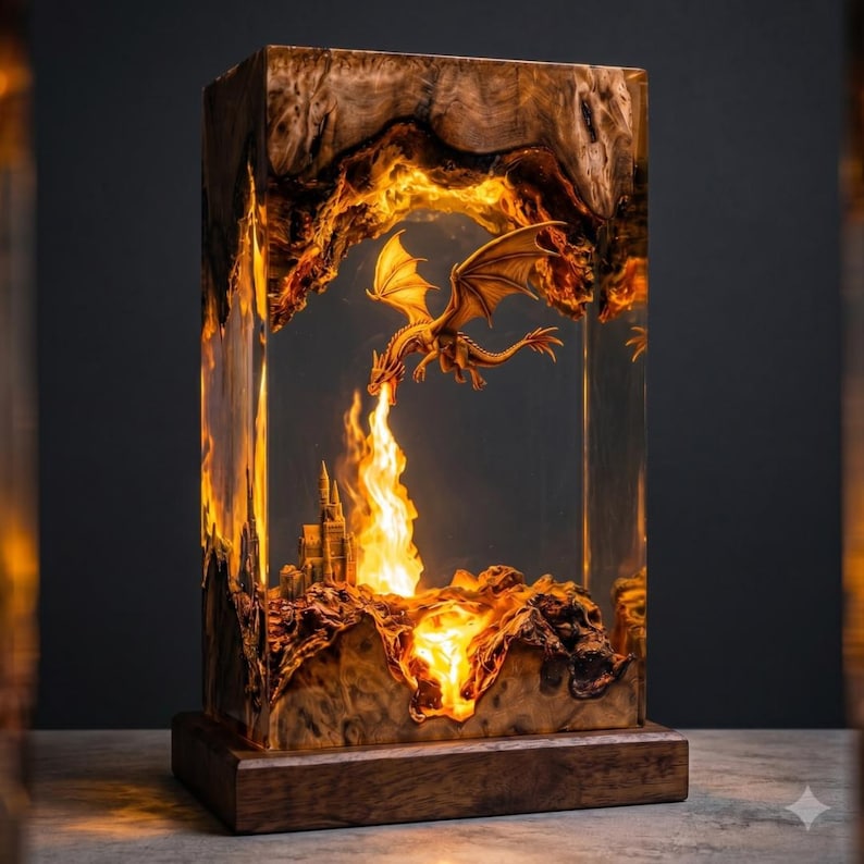 May include: A rectangular lamp made of natural wood and clear resin. Inside the resin, a miniature dragon is suspended in flight above a small castle. The lamp emits a warm, glowing orange light that illuminates the dragon and the castle.