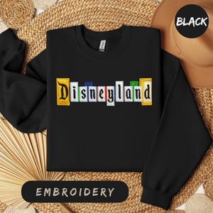 May include: A white ceramic mug with a black handle and the text "But First, Coffee" in a handwritten style. The mug is on a white surface. The mug is 10 cm tall.