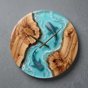 May include: A round wall clock featuring two natural wood slabs with a central turquoise resin inlay that mimics ocean waves. Two whale shark figures are embedded within the resin, and thin gold metal lines serve as hour markers with matching hands.