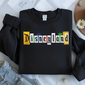 May include: A white ceramic mug with a black handle and the text "But First, Coffee" in a bold, black font. The mug is filled with a dark liquid, likely coffee, and rests on a light-coloured surface.