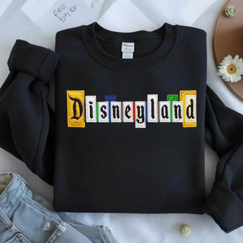 May include: A white ceramic mug with a black handle and the text "But First, Coffee" in a bold, black font. The mug is filled with a dark liquid, likely coffee, and rests on a light-coloured surface.