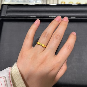 A close-up view of a hand wearing a gold ring on the ring finger.