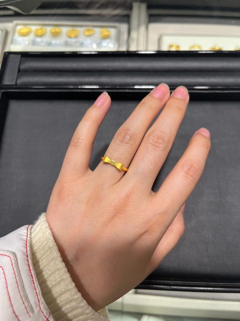 A close-up view of a hand wearing a gold ring on the ring finger.