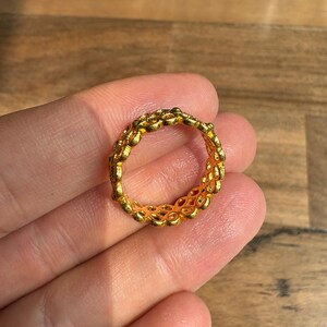 A gold ring is being held in a person's hand against a wooden background.