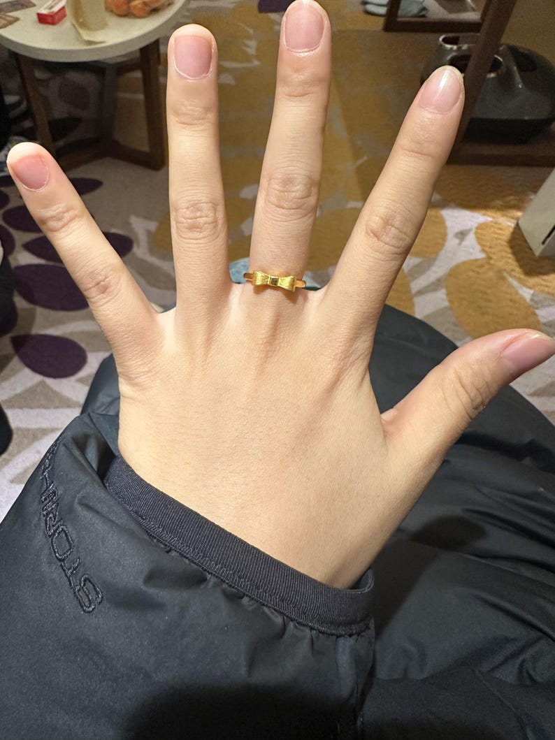 A close-up of a person's hand wearing a gold ring on the ring finger.
