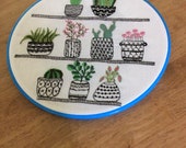 Hand embroidered hoop wall hanging, cacti succulent house plants in hoop wall hanging, monochrome pots with green and pink plants