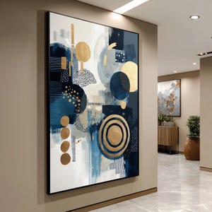 Könnte beinhalten: Abstrakte Wandkunst mit modernem Design in Marineblau, Gold und Weiß. Das Kunstwerk zeigt Kreise, Punkte und lineare Elemente, die eine zeitgenössische Ästhetik schaffen. Die gerahmte Leinwand wird in einem Flur ausgestellt.