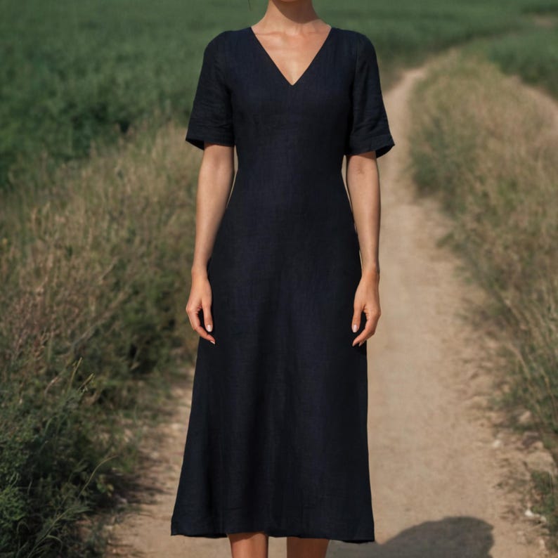 K&ouml;nnte beinhalten: Dunkelmarineblaues V-Ausschnitt-Kleid mit kurzen &Auml;rmeln. Das Kleid hat ein schlichtes, elegantes Design und reicht bis zur Mitte der Wade. Das Kleid ist aus einem strukturierten Stoff gefertigt und f&uuml;r verschiedene Anl&auml;sse geeignet.