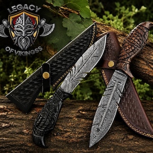 May include: Two fixed-blade knives with Damascus steel blades featuring feather-like patterns and carved dark wood handles. Each knife includes a leather sheath with a brass snap button. The logo Legacy of Vikingss is visible in the corner.
