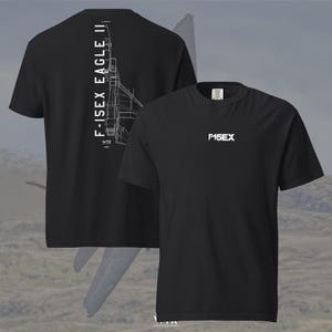 May include: A black short-sleeve t-shirt featuring a white graphic on the front chest that reads F-15EX. The back of the shirt displays a vertical white line drawing of an F-15EX Eagle II fighter jet with the text F-15EX EAGLE II printed vertically.