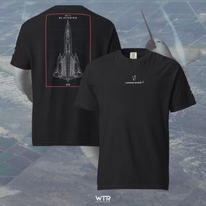 Op de afbeelding: Een zwart t-shirt met korte mouwen met op de achterkant een witte technische lijntekening van een SR-71 Blackbird-vliegtuig, omsloten door een rode rechthoekige rand met de tekst SR-71 BLACKBIRD. De voorkant toont het Lockheed Martin-logo.
