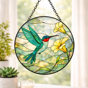 Puede incluir: Vidriera redonda que representa un colibrí en vuelo y flores amarillas. El colibrí tiene alas turquesas y garganta roja. El fondo es una mezcla de verde, azul y amarillo. Una cadena negra está unida para colgar.