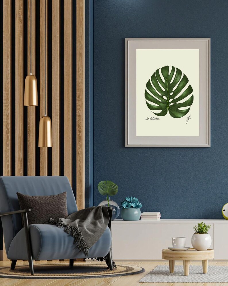 Monstera print in a white frame with passpartout hanging on a blue wall