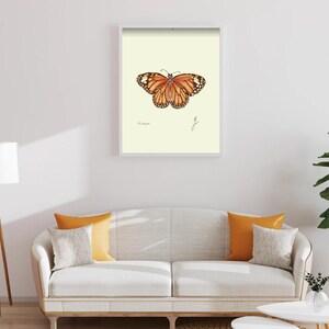 Monarch print in a white framed print on a white wall above a white couch