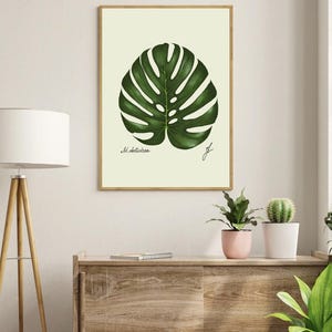 Monstera print in a wooden frame hanging on a white wall