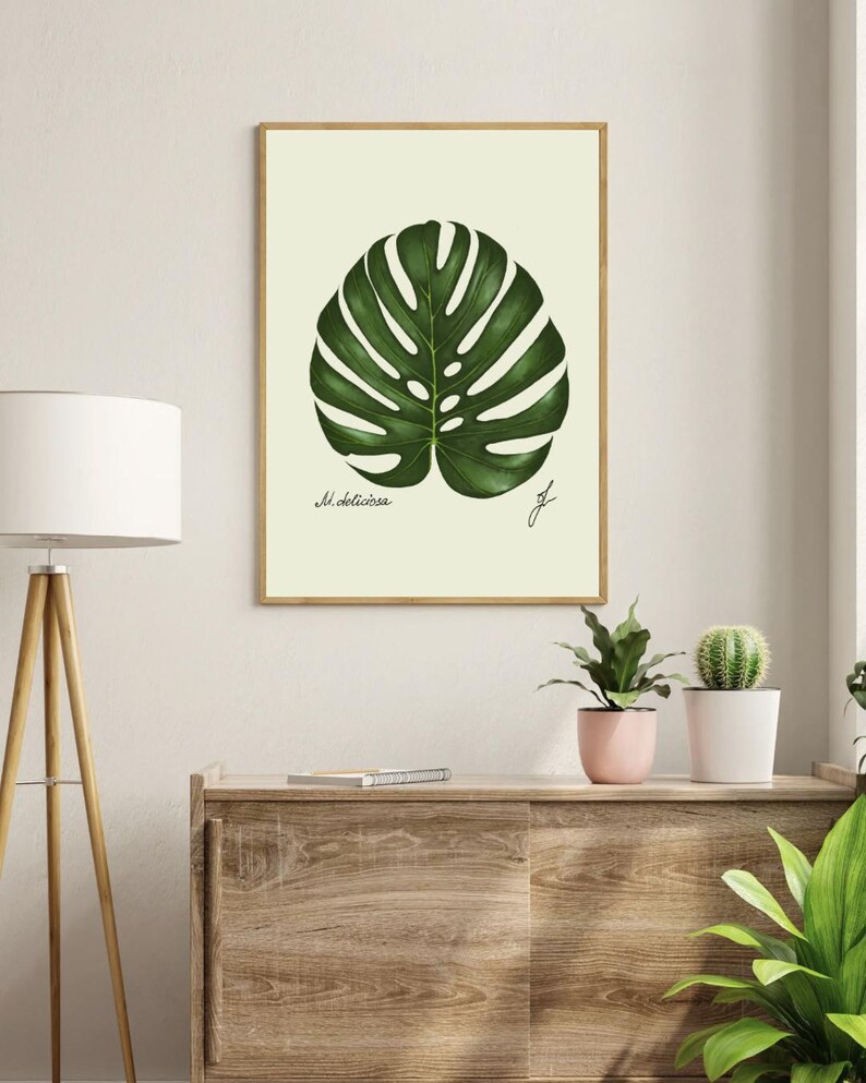 Monstera print in a wooden frame hanging on a white wall