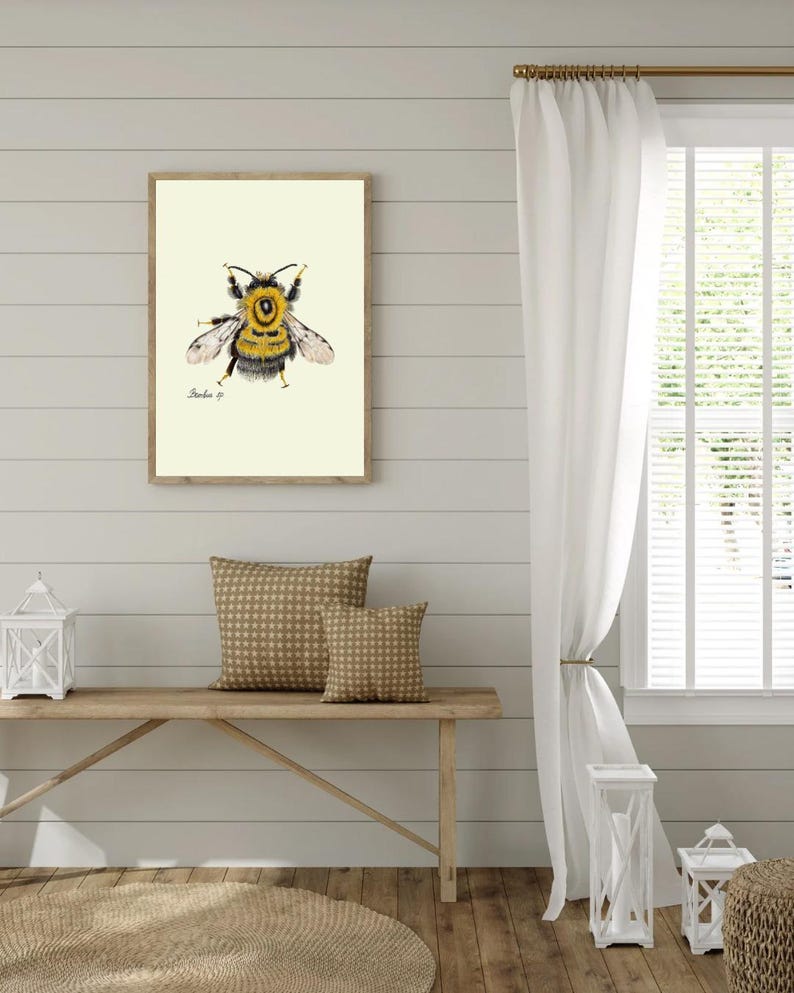 Bumblebee print hanging on a wooden cabin wall above a bench with two brown pillows