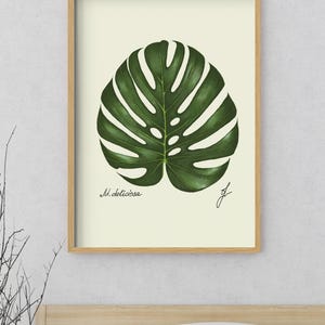 Monstera print in a wooden framed print above a bed
