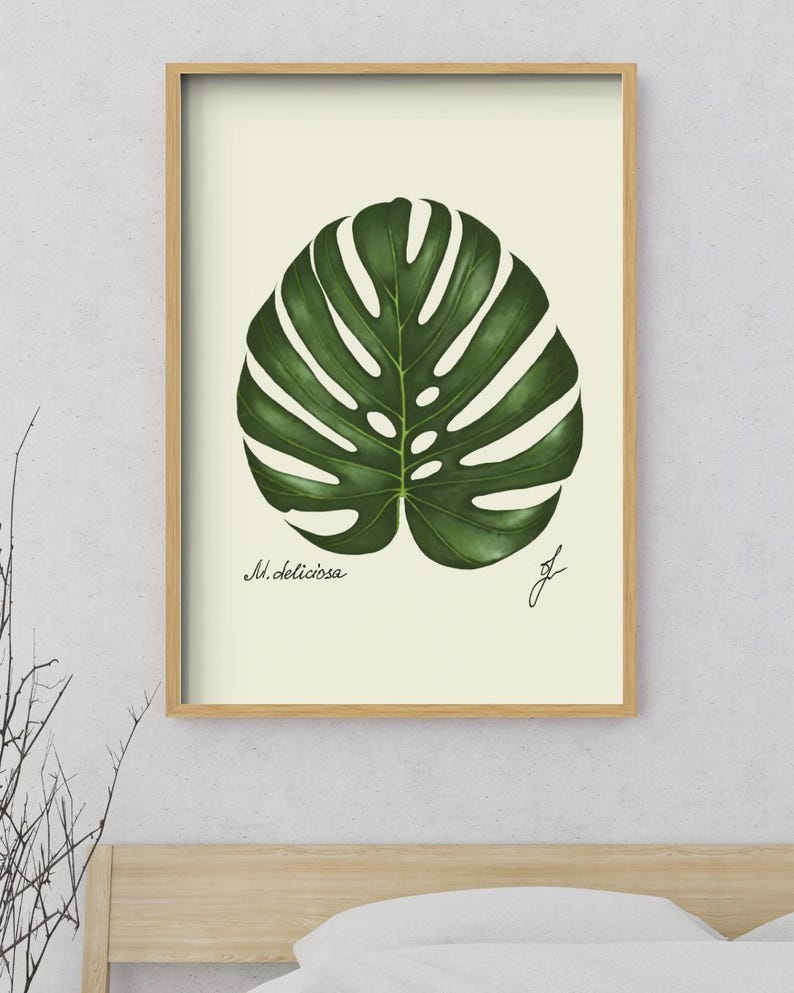 Monstera print in a wooden framed print above a bed