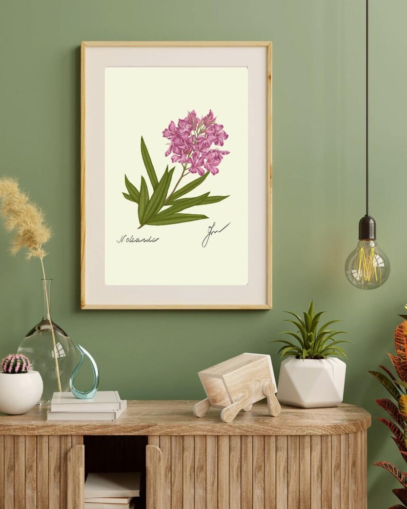 Oleander print in a wooden frame with white passpartout hanging on a green wall above the dresser