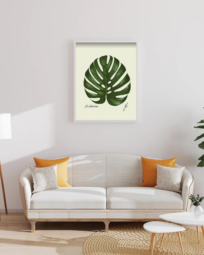 Monstera print in a white framed print on a white wall above a white couch