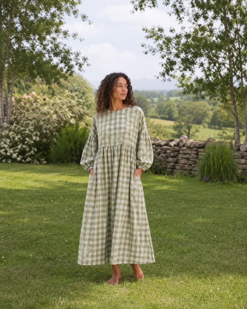 Pode incluir: Um vestido de manga comprida at&eacute; ao tornozelo com um padr&atilde;o de xadrez vichy em verde s&aacute;lvia e branco. A pe&ccedil;a tem um decote redondo, uma cintura franzida, mangas volumosas com punhos ajustados e dois bolsos laterais.