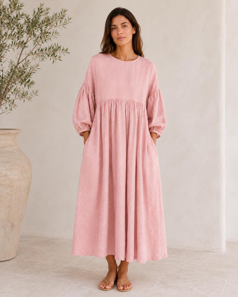 Pode incluir: Um vestido midi em tom rosa seco com decote redondo, mangas compridas volumosas com punhos franzidos e uma saia fluida e descontra&iacute;da com bolsos laterais. A pe&ccedil;a &eacute; confecionada em tecido texturizado e termina a meio da barriga da perna.