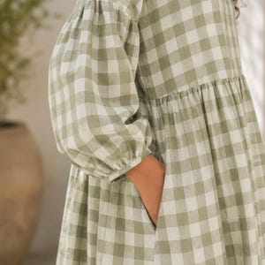 Pode incluir: Um vestido com padr&atilde;o xadrez vichy em verde s&aacute;lvia e branco, com mangas compridas e volumosas tipo bal&atilde;o com punhos franzidos e cintura franzida. O vestido inclui um bolso lateral funcional integrado na costura da saia.