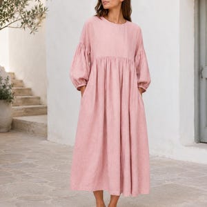 Pode incluir: Um vestido midi em rosa empoeirado com decote redondo, mangas compridas volumosas com punhos franzidos e uma saia relaxada e fluida com cintura franzida. A pe&ccedil;a &eacute; confeccionada em tecido texturizado e inclui bolsos laterais.