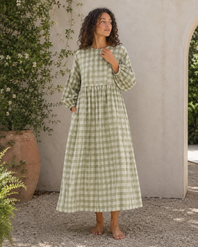 Pode incluir: Um vestido de manga comprida e comprimento at&eacute; ao tornozelo com um padr&atilde;o de xadrez vichy em verde s&aacute;lvia e branco. A pe&ccedil;a apresenta um decote redondo, uma cintura franzida e mangas largas com punhos el&aacute;sticos, criando uma silhueta fluida.