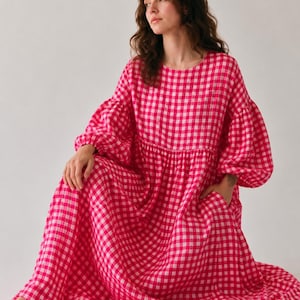 Pode incluir: Um vestido de manga comprida e comprimento at&eacute; ao ch&atilde;o com um padr&atilde;o vibrante de xadrez vichy em rosa choque e branco. A pe&ccedil;a tem decote redondo, cintura franzida, mangas bal&atilde;o volumosas com punhos el&aacute;sticos e bolsos laterais.