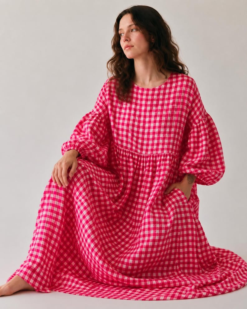 Pode incluir: Um vestido de manga comprida e comprimento at&eacute; ao ch&atilde;o com um padr&atilde;o vibrante de xadrez vichy em rosa choque e branco. A pe&ccedil;a tem decote redondo, cintura franzida, mangas bal&atilde;o volumosas com punhos el&aacute;sticos e bolsos laterais.