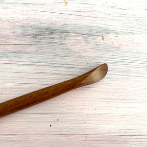 May include: A wooden tool with a rounded end, perfect for smoothing out clay or other materials.
