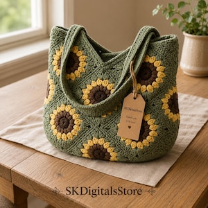May include: A crochet tote bag made of olive green yarn squares featuring yellow and brown sunflower motifs. The bag has two handles and a brown paper tag attached with twine that reads SKDigitalsStore, Handmade with Love, and a heart symbol.
