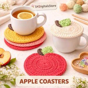Könnte beinhalten: Gehäkelte Untersetzer in Apfelform in Gelb, Rosa und Rot. Eine weiße Tasse mit Tee und einer Zitronenscheibe steht auf den Untersetzern. Das Bild zeigt auch einen roten Apfel-Untersetzer und eine weiße Tasse mit gehäkeltem Deckel. Durchmesser ca. 10 cm.