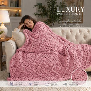 May include: A dusty rose knitted blanket with a diamond pattern is draped over a sofa. The blanket is thick and appears soft. The words "LUXURY KNITTED BLANKET" and "Snuggle in Style" are displayed in the image.