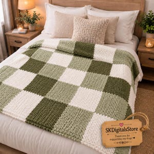 May include: A chunky knit throw blanket featuring a checkered pattern in alternating shades of sage green, olive green, and cream. A rectangular tan paper tag is attached with twine, printed with the text SKDigitalsStore Thank you for supporting my shop.
