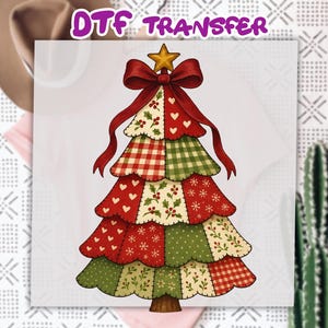 May include: DTF TRANSFER text above a Christmas tree design. The tree is composed of patchwork sections in red, green, and cream, adorned with hearts, snowflakes, and holly. A red bow and gold star top the tree. The tree has a brown trunk.