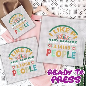 May include: White sublimation transfer sheets with the text "I Like Pi and Maybe 3.14159 People" in a colorful design. The phrase "Ready to Press" is also visible. A pink t-shirt and a brown hat are in the background.